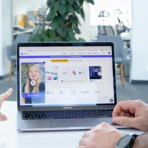 Two colleagues working together on a laptop screen in a modern office setting.