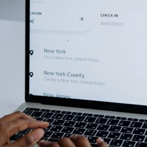 Hands typing on a laptop near New York location search screen.