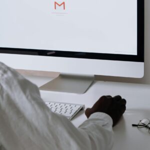 A professional in an office setting checking emails on a desktop computer with a clean workspace.
